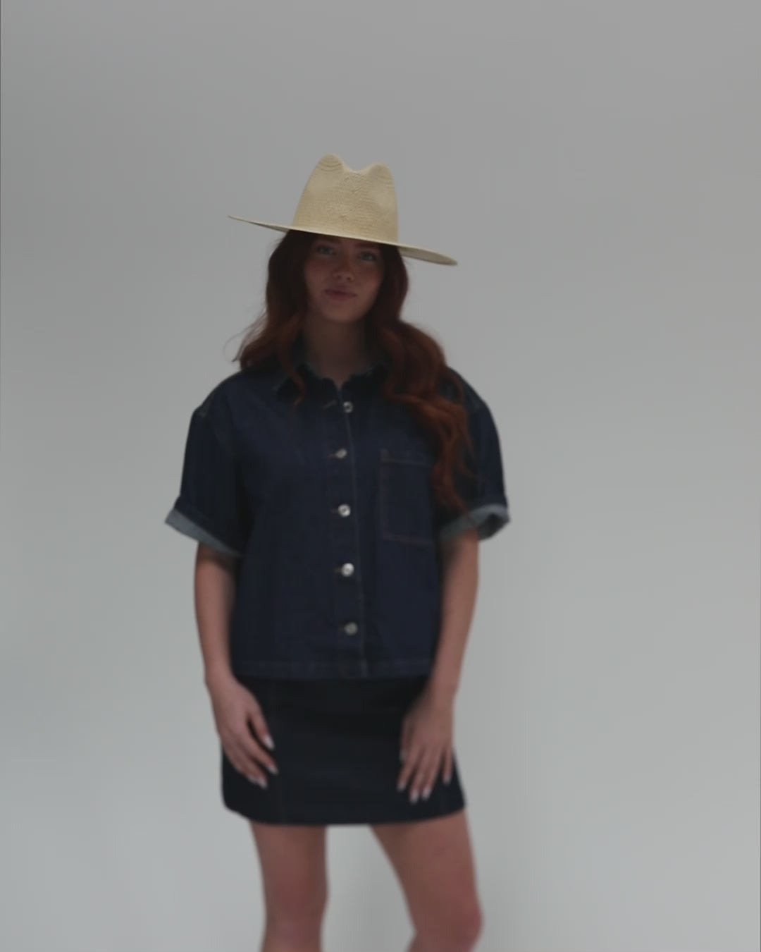 Woman wearing a natural colored wide brim fedora straw hat, a denim shirt and a denim skirt against a plain background #color_natural