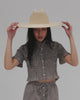 Woman wearing a natural colored western wide brim straw hat and a grey outfit against a plain background #color_natural