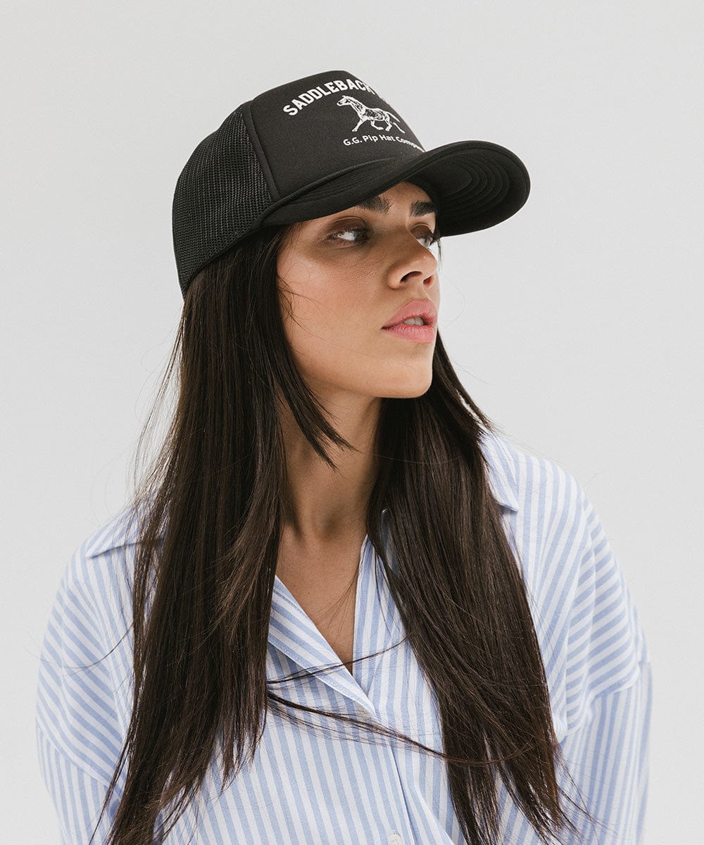Woman wearing a black cap with 'Saddleback Ranch' text and logo and a light colored shirt, looking sideways  against a plain background #color_black 
