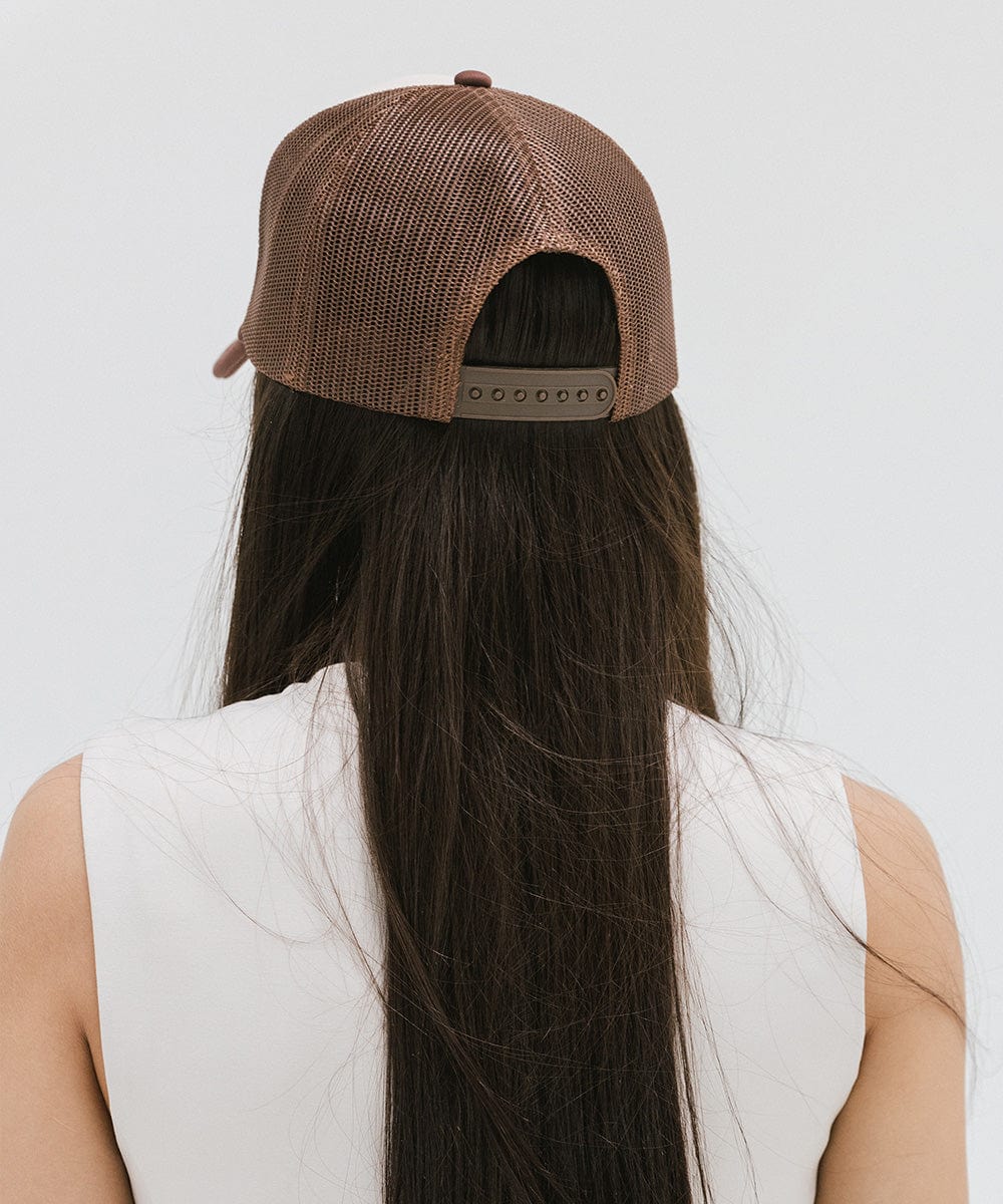 Woman wearing a brown cap and a white top against a plain background  #color_cream - chocolate brown