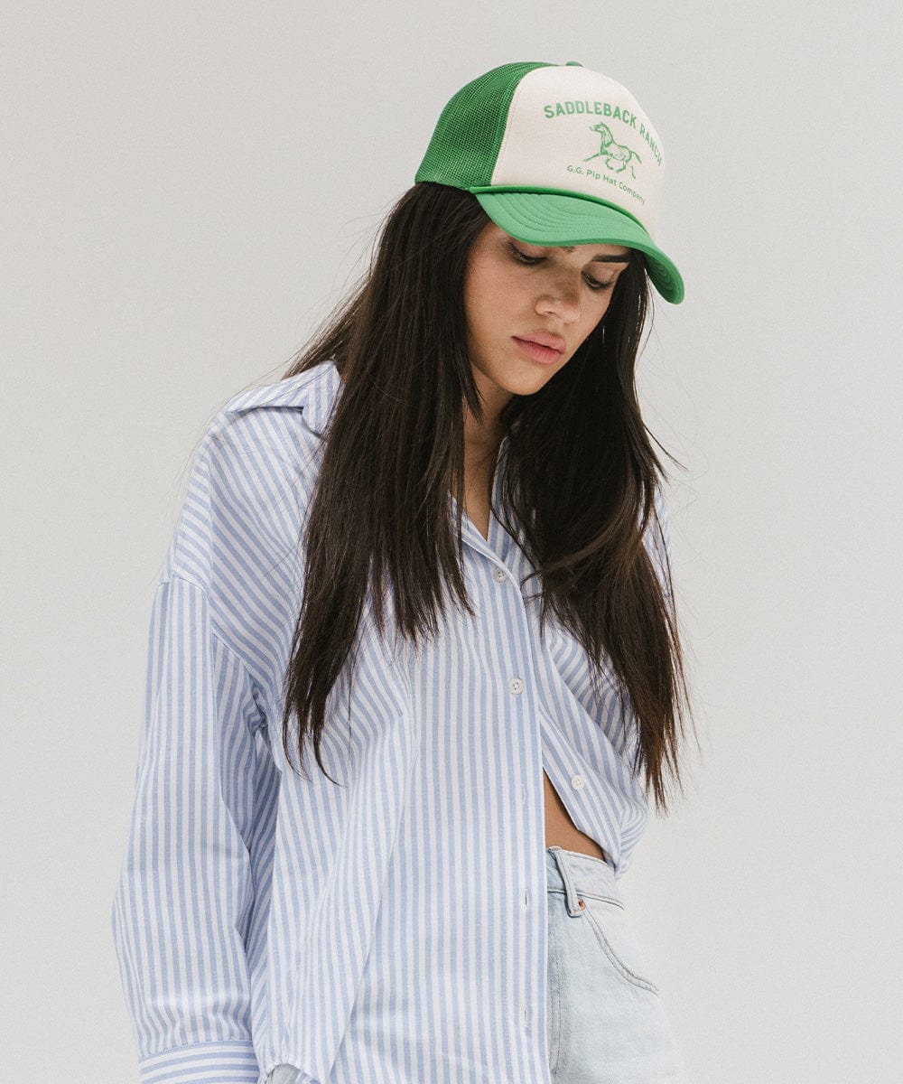 Woman wearing a cream and vintage green cap with 'Saddleback Ranch' text and logo, and a shirt, posing  against a plain background #color_cream - vintage green