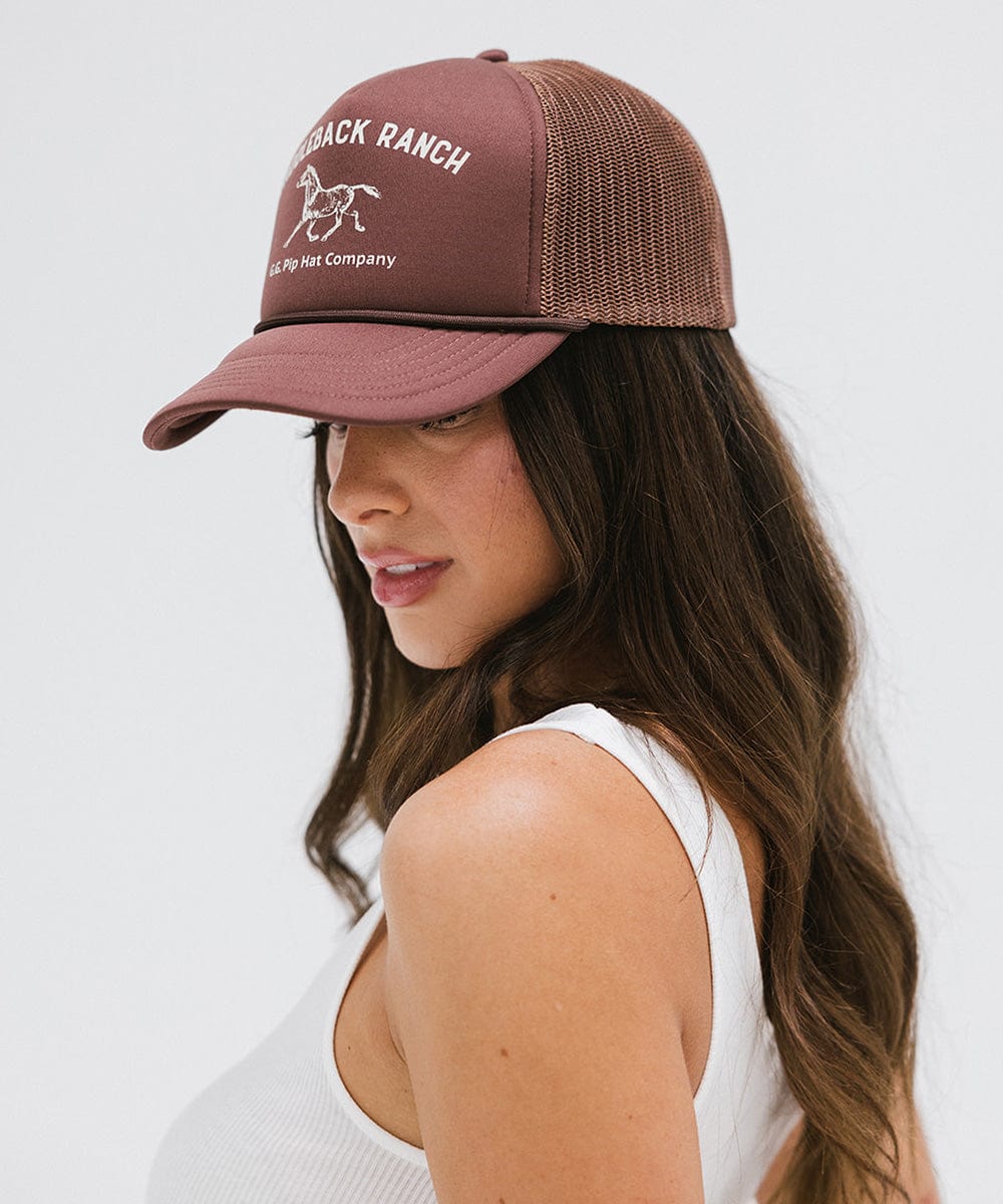 Woman wearing chocolate brown cap with 'Saddleback Ranch' text and logo, and a white top, posing sideways against a plain background  #color_chocolate brown