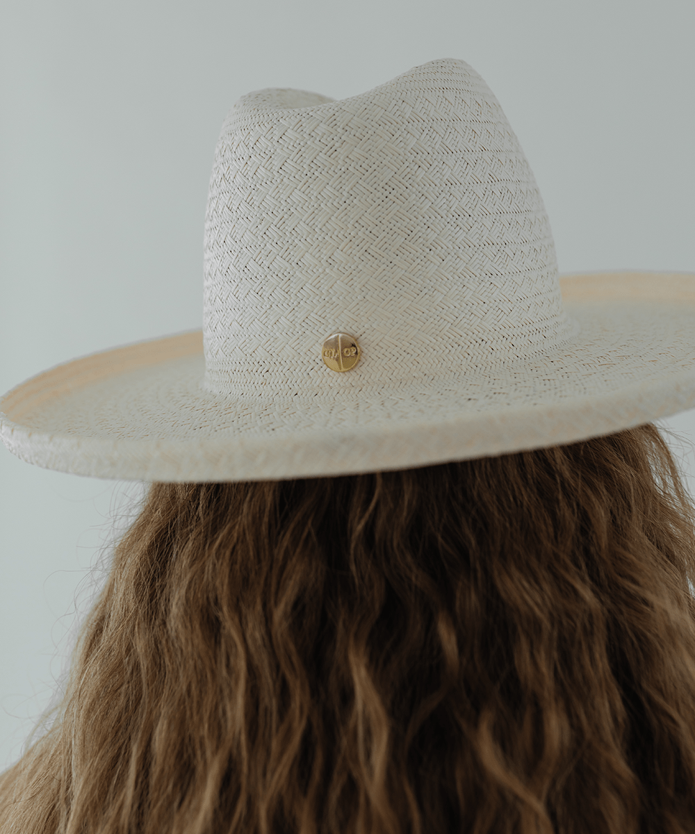 Person wearing a white pencil brim straw hat against a plain background #color_white