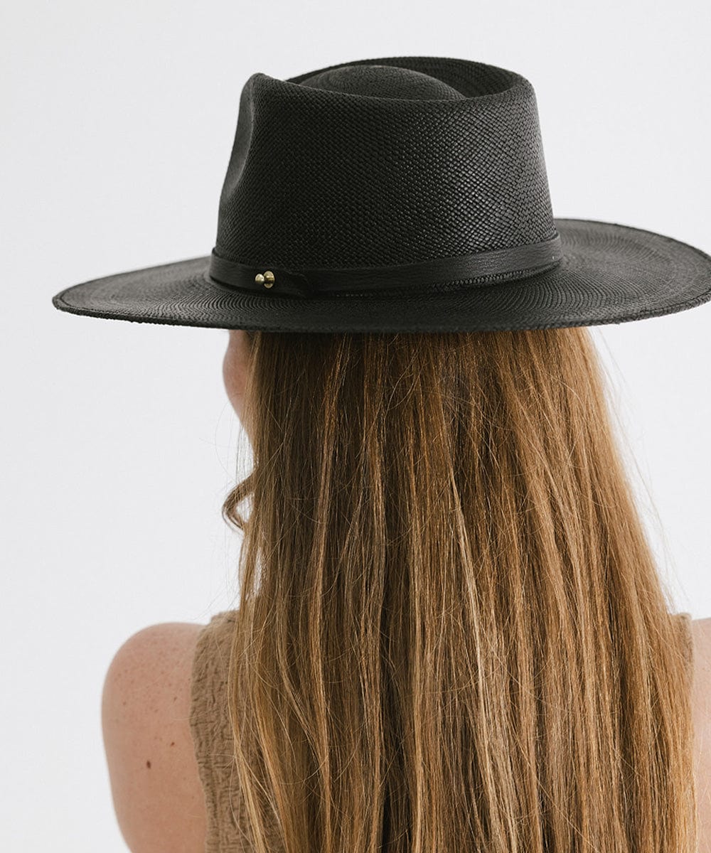 Person with long hair wearing a black straw hat with a hat band against a plain background #color_black
