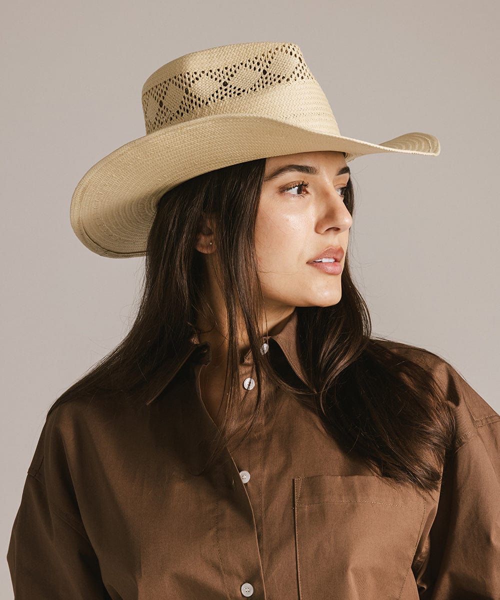 Woman wearing a natural colored straw hat and a brown shirt, looking sideways against a plain background #color_natural 