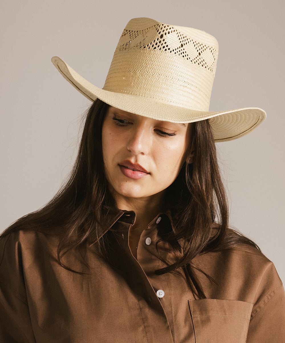 Woman wearing a natural colored straw hat and a brown shirt, posing against a plain background #color_natural 
