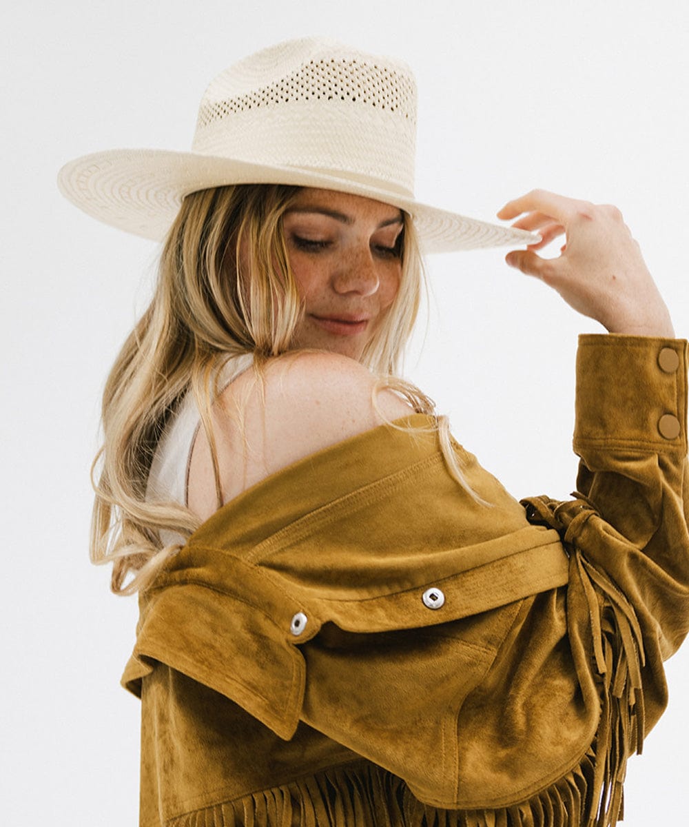 Woman wearing a natural colored straw cowboy hat and a mustard colored jacket, posing against a plain background  #color_natural