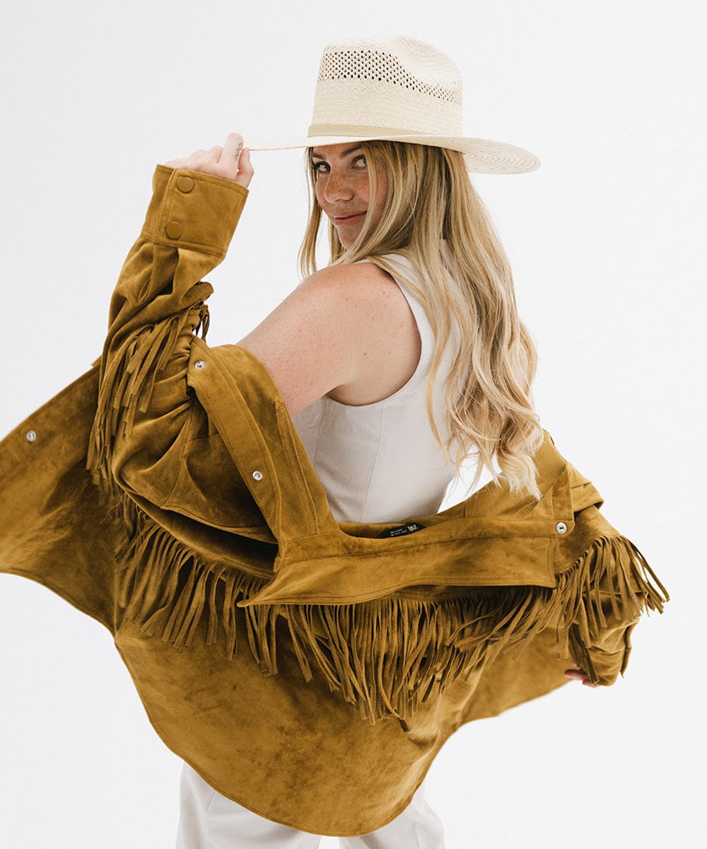 Woman wearing a natural colored straw cowboy hat, a white top with a mustard jacket, posing against a plain background  #color_natural