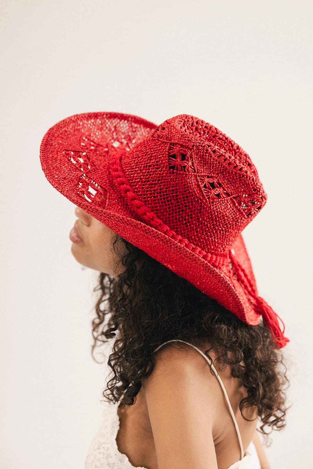 Woman wearing a red crochet cowboy hat against a plain background #color_cherry red