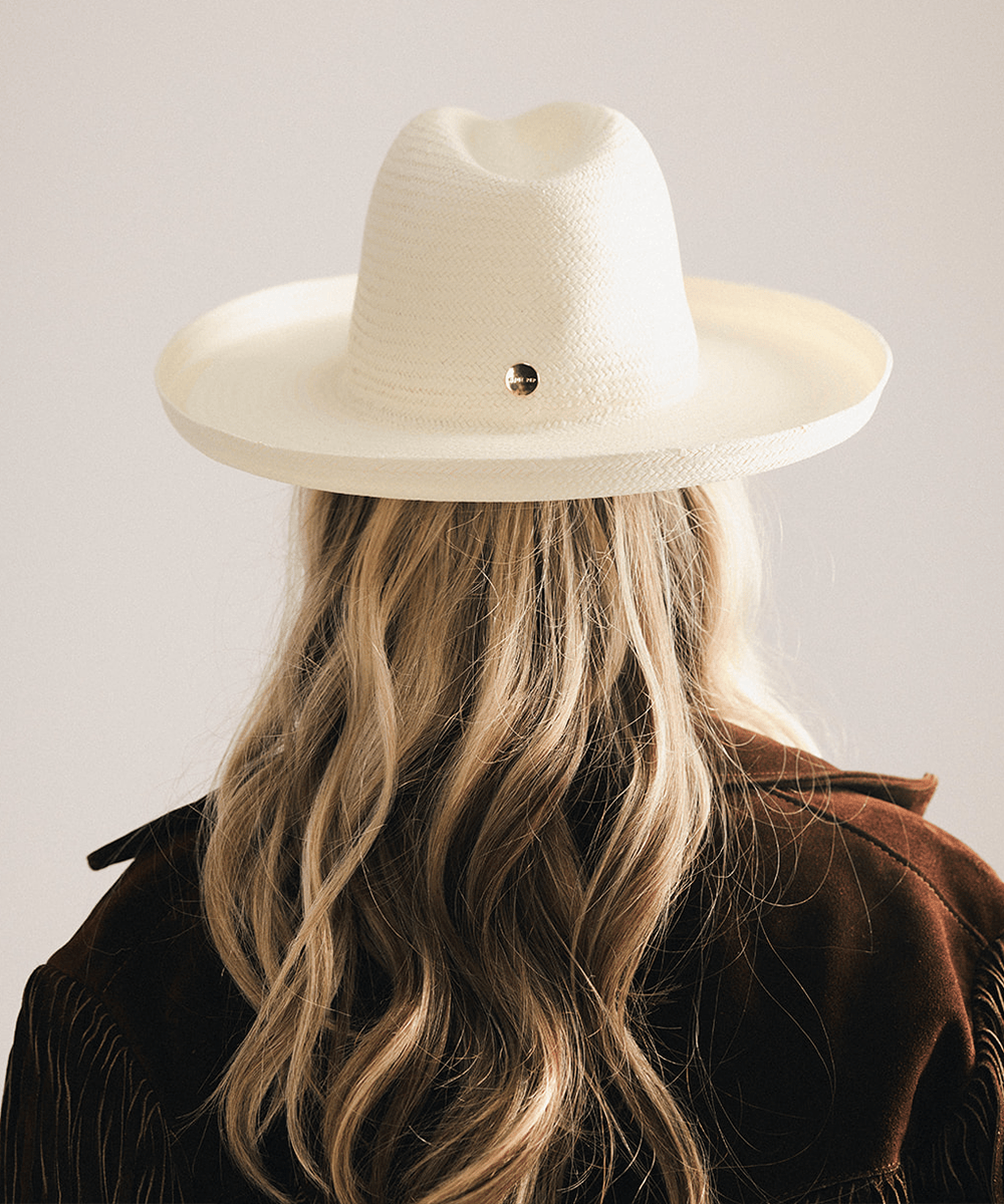 Woman wearing a white pencil brim fedora hat made of paper straw, displayed against a white background. #color_white