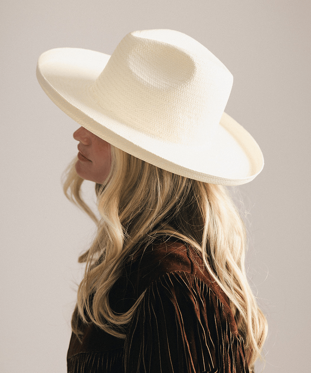 Woman wearing a white pencil brim fedora hat made of paper straw, displayed against a white background. #color_white