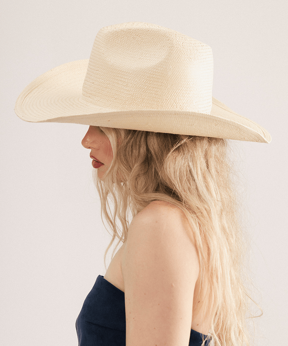 Woman wearing a natural colored straw cowboy hat with a fedora crown and a rolled western brim, displayed on a white background. #color_natural 