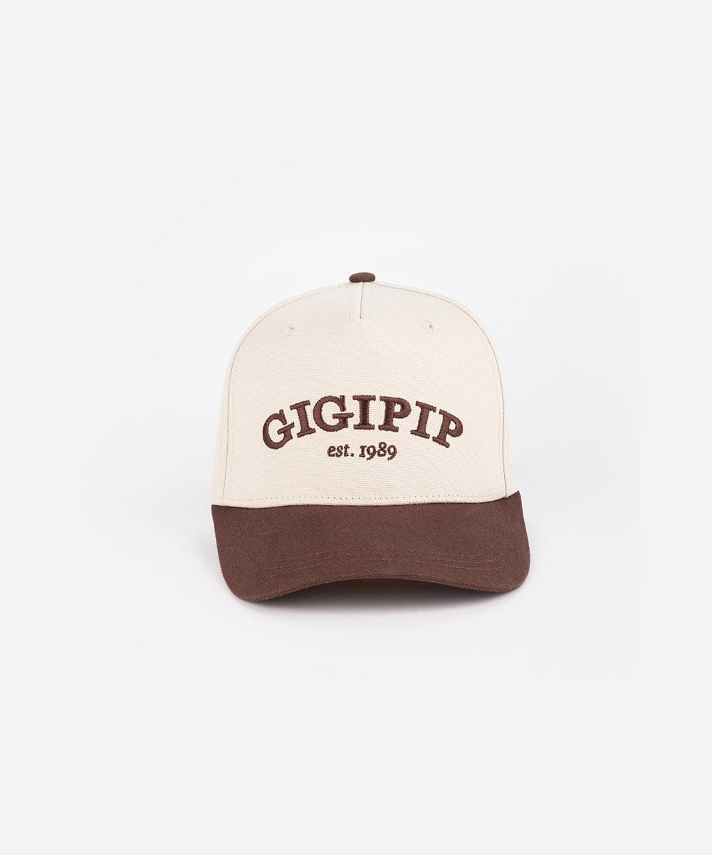 A cream and chocolate brown trucker hat with 'GIGI PIP' embroidered in chocolate brown on the front against a plain background  #color_cream - chocolate brown