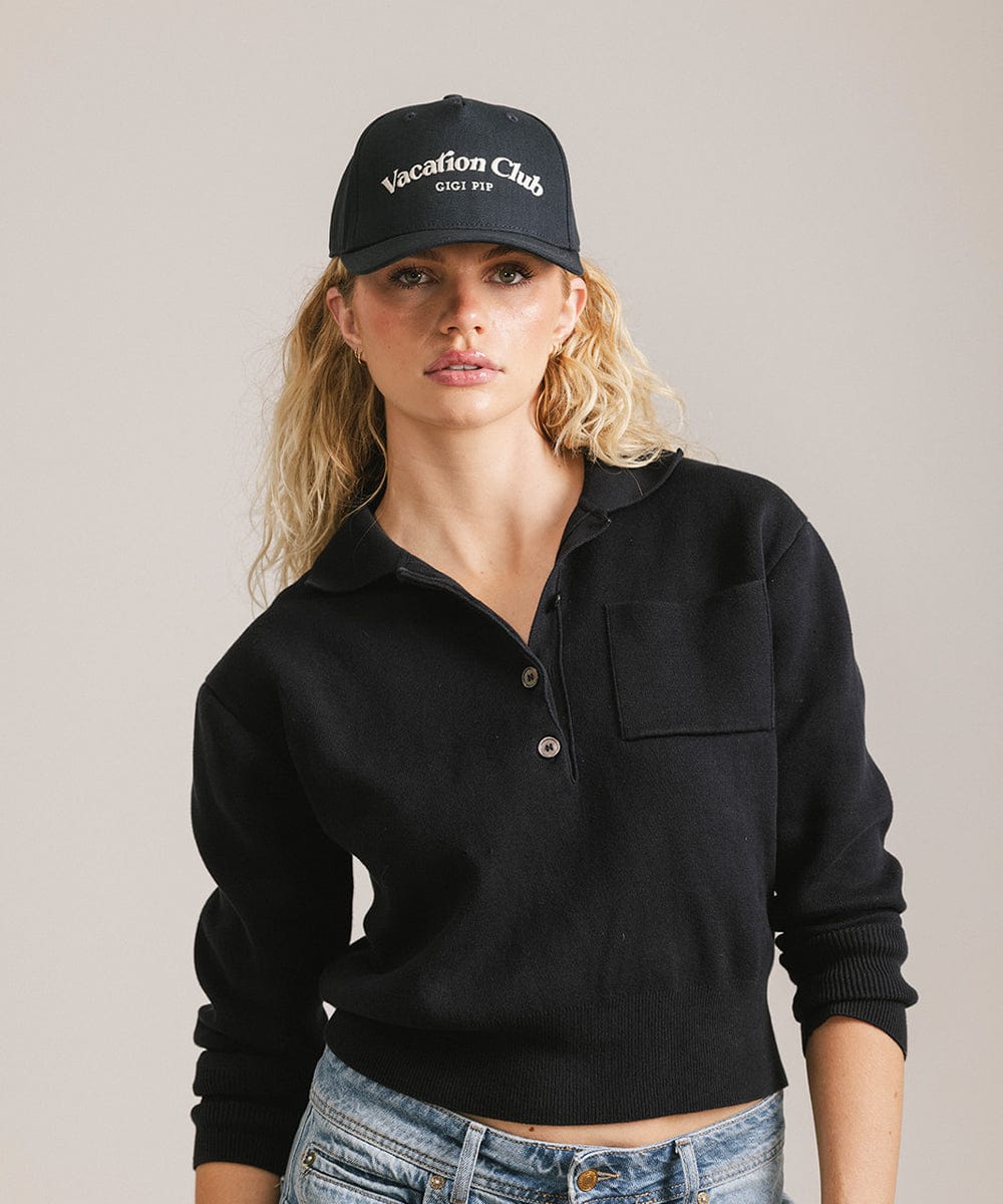 Woman wearing a navy cap with 'Vacation Club' text and a black shirt against a plain background  #color_navy