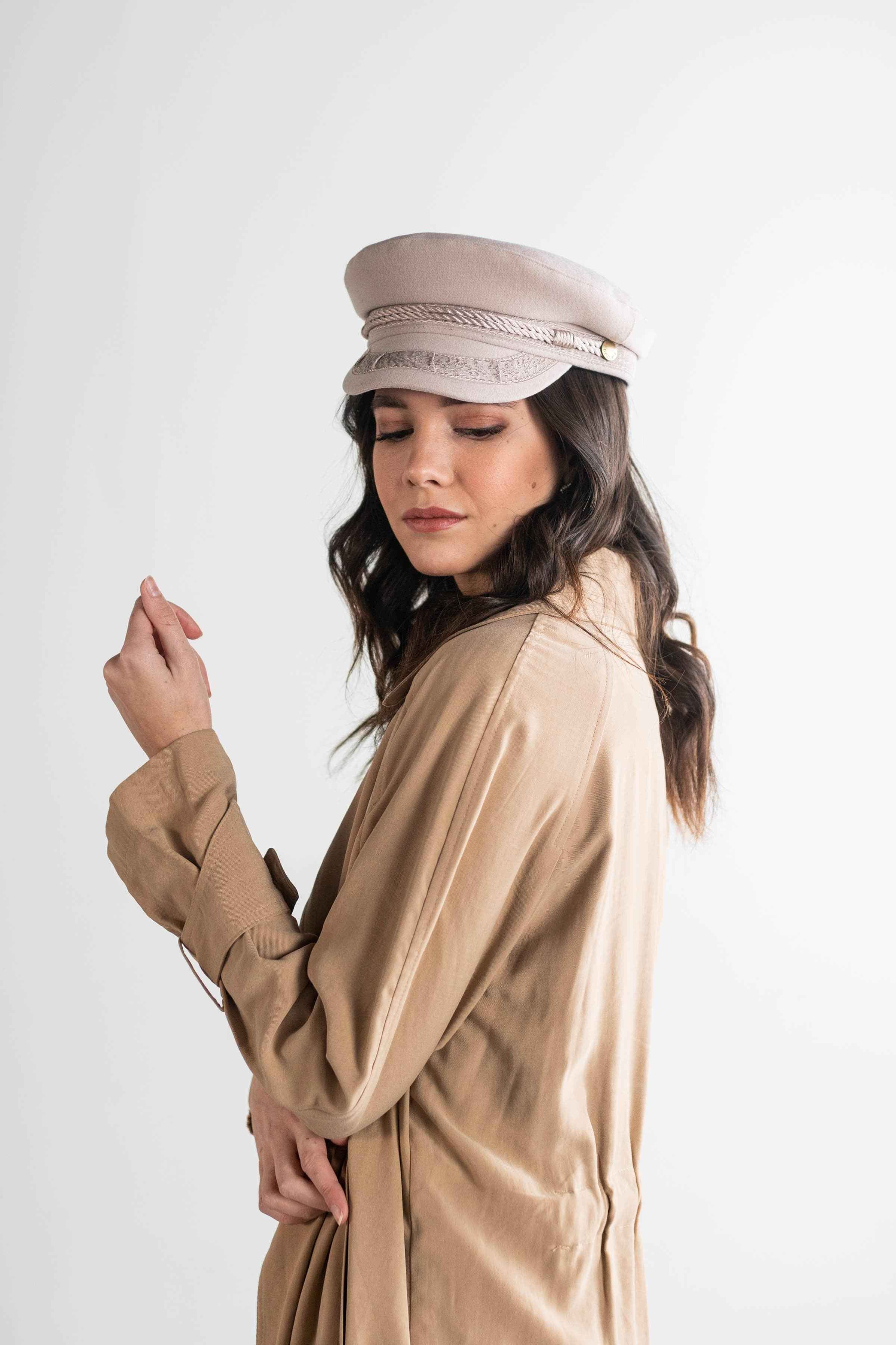 Woman wearing an ivory colored lieutenant cap and a brown shirt with a brown jacket, posing against a plain background #color_ivory