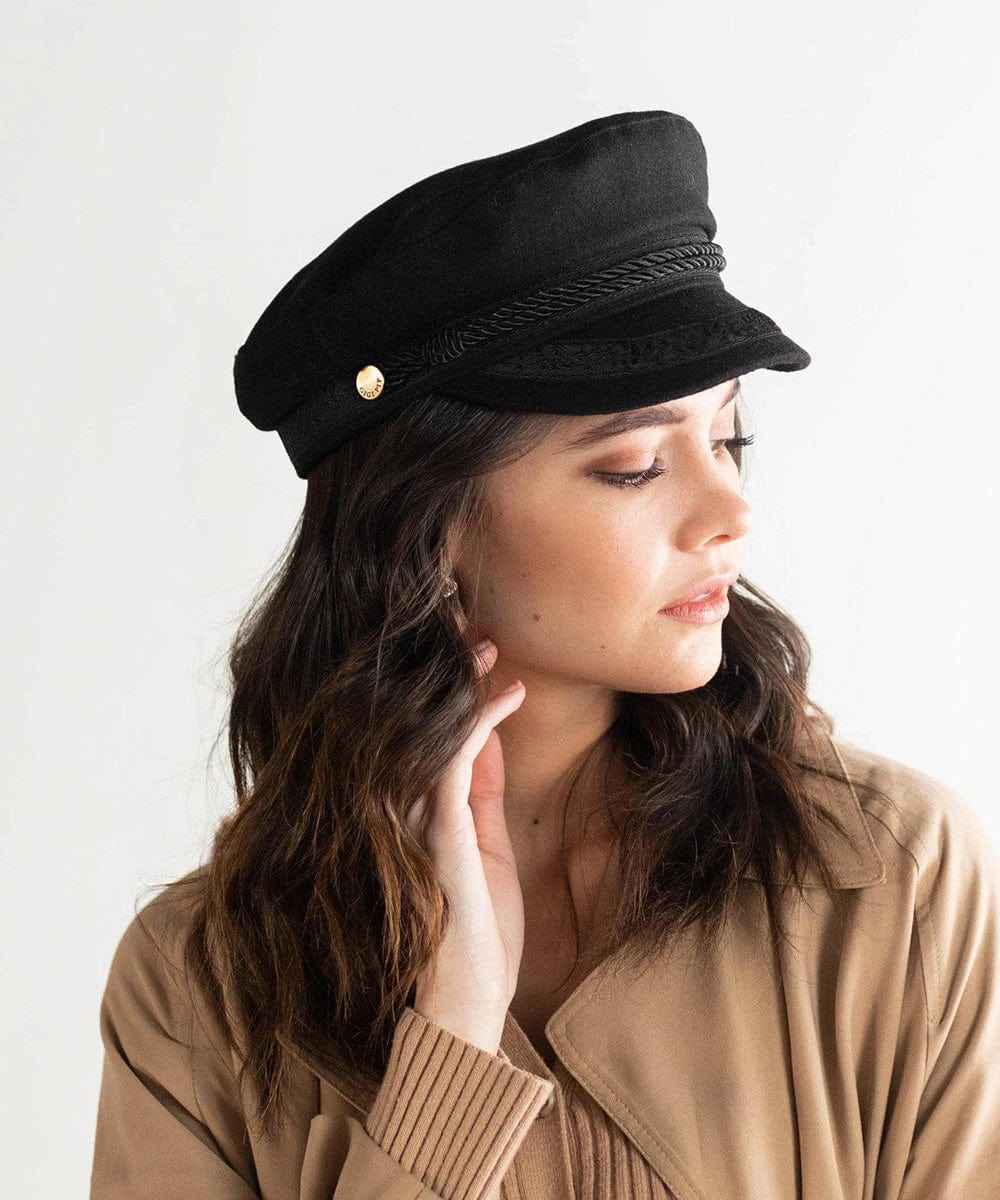 Woman wearing a black lieutenant  cap and a beige jacket, posing sideways against a plain background #color_black