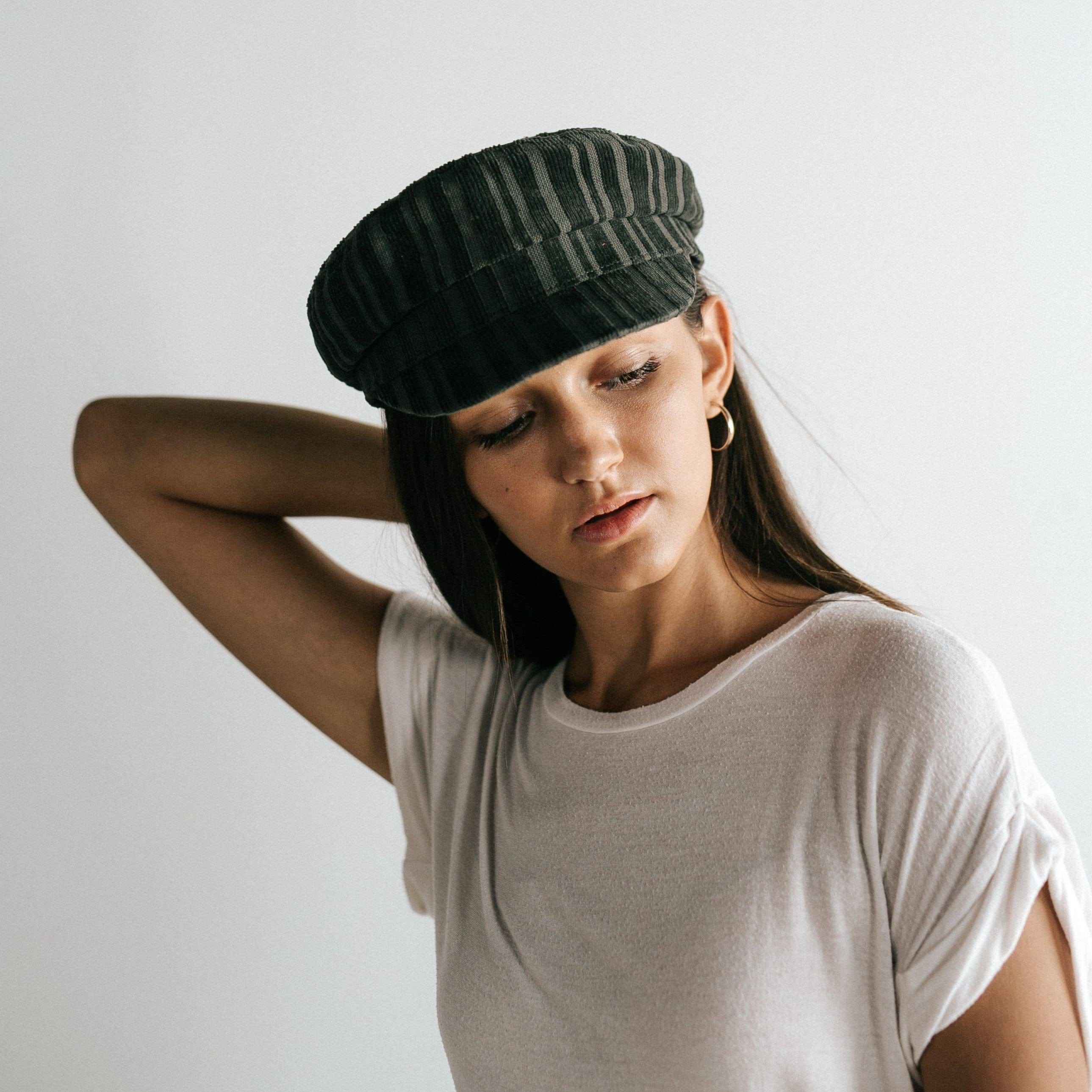 Woman wearing a forest green colored striped cap and a white t-shirt, posing sideways against a plain background  #color_forest green